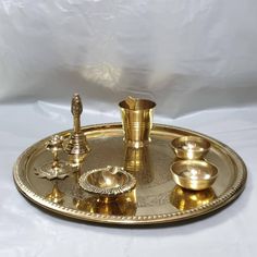 a brass tray with cups and candles on it