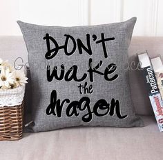 a pillow that says don't wake the dragon on it next to some books