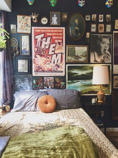 a bed sitting in a bedroom next to a bunch of pictures on the wall above it