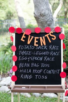 a sign that says events on it in front of a tree and bushes with red pom - poms