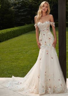 a woman in a wedding dress posing for the camera outside with her hand on her hip