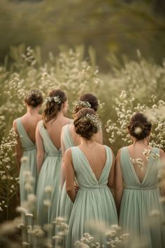 four bridesmaids are standing in the middle of a field with tall grass and wildflowers