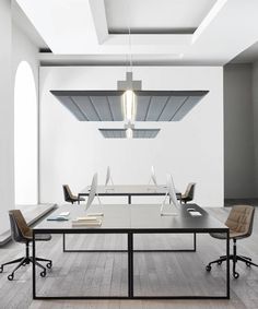 an empty conference room with two desks and chairs in front of a window that is lit by a pendant light