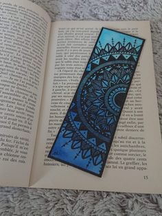 an open book with a blue and black design on the cover is laying on a carpet