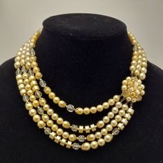 Step back in time with this beautiful 1950s vintage necklace. Features a cluster of pale yellow faux pearl beads that connects to multiple strands of clear glass beads, pale yellow faux pearl beads in different shapes and beautiful gold tone findings, complimenting each other very well. Easy to wear with a gold tone hook clasp. Treat yourself to this vintage gem or gift a loved one who adores vintage accessories, this necklace is sure to become a favorite in any vintage jewelry collection. Signed JAPAN. Circa 1950s/1960s. TO VIEW MORE FROM NEW VINTAGE FOR YOU, GO HERE: https://newvintageforyou.etsy.com All vintage items are sold as is in pictured condition. I do not alter or repair any vintage items because I feel it is important to maintain the authentic history of the piece. The photos a Twist Beads, Multi Strand Beaded Necklace, Vintage Beads Necklace, Vintage Necklaces, Hook Clasp, Multi Strand Necklace, Jewelry Companies, 1950s Vintage, Pale Yellow