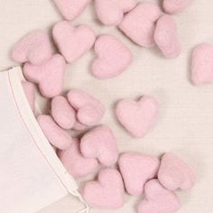 small pink hearts are scattered on a white surface next to a drawstring bag