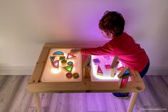 a young child playing with an illuminated wooden table