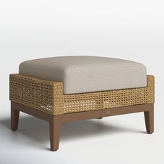 the foot stool is made out of wicker and has a cushion on one end