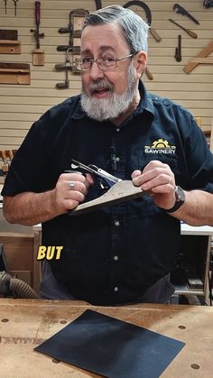 an older man is working with wood in his shop while holding a pair of pliers