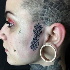 a woman with tattoos on her face and ear