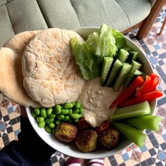 a bowl filled with vegetables and pita bread on top of a checkered table