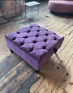 a purple ottoman sitting on top of a wooden floor