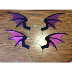 two purple and black dragon wings on a wooden table with wires in the shape of a heart