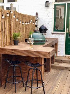 an outdoor bar with two stools and a grill on the back deck in front of a house