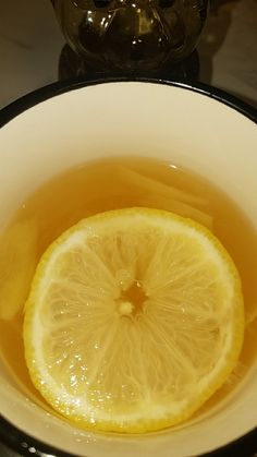 a bowl filled with liquid and a slice of lemon on top of the tea in it