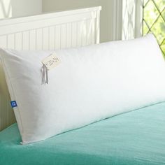 a white pillow sitting on top of a bed next to a green comforter and window