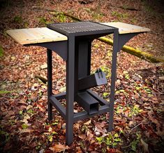 an outdoor table made out of wood and metal in the middle of leaves on the ground