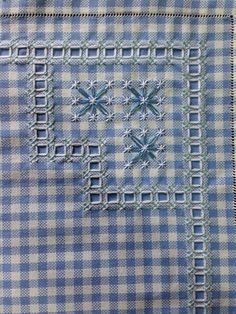 a blue and white checkered shirt with an embroidered cross