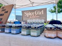 jars of jams are sitting on a table under a tent