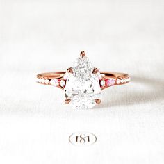 an oval shaped diamond ring with pink and white stones on the band, set in 18k rose gold