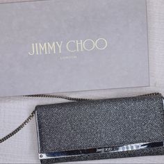 Jimmy Choo. Inject Milla Anthracite Instant Elegance Into Evening Ensembles With The Emmie Clutch Bag From Jimmy Choo With An Iridescent Glitter Exterior. Structured And Compact, The Slim Silhouette Opens Via An Asymmetric Flap Front To A Smooth Interior With Practical Card Slots And A Zipped Pouch, Keeping Money And Essentials Housed Safely As It Swings From The Optional Chain Strap. Silver Party Bags With Silver-tone Logo Plaque, Evening Bag With Silver-tone Logo Plaque In Metallic Silver, Metallic Silver Evening Bag With Logo Plaque, Metallic Silver Evening Bags With Silver-tone Logo Plaque, Silver Evening Bag With Silver-tone Logo Plaque, Silver Evening Bag With Dust Bag For Party, Luxury Metallic Silver Bags For Party, Luxury Metallic Silver Party Bag, Luxury Metallic Silver Party Bags