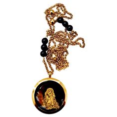 Introducing a handcrafted, one-of-a-kind necklace that combines vintage charm with artistic flair. This striking piece features a truly unique vintage locket pendant, showcasing an exquisite black onyx backing. The locket is adorned with a mesmerizing gold leaf design depicting a long-haired goddess with a giant moon and twinkling stars, capturing the essence of celestial beauty. Measuring 1.5 inches, the pendant is elegantly suspended on a vintage brass chain, which is embellished with black on