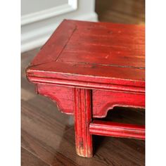 an old red wooden table sitting on top of a hard wood floor