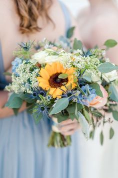 a bridesmaid holding a bouquet of sunflowers and greenery