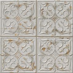 an old white tile wall with gold and silver designs on the tiles, as well as letters