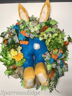 a stuffed animal sitting in the middle of a wreath with flowers and leaves around it