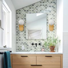 a bathroom with a large mirror above the sink and wooden cabinet below it, next to a window