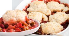 a white bowl filled with fruit cobbler next to a spoon