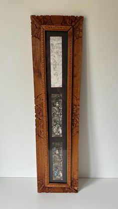 an old wooden frame with pictures on the front and sides, sitting against a white wall