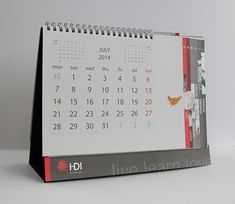 a desk calendar sitting on top of a white table next to a red and black pen