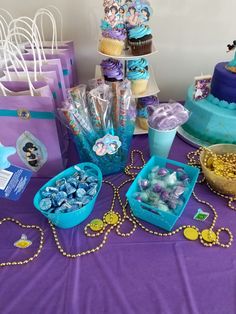 a table topped with lots of blue and purple desserts next to cupcakes