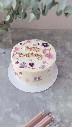 a birthday cake sitting on top of a table next to a vase filled with flowers