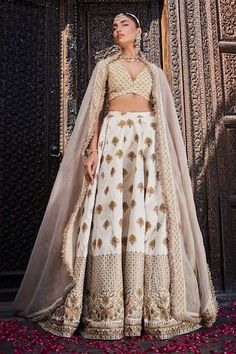 Ivory silk lehenga with an attached cancan and gold floral embroidery. Comes with a padded blouse and a dupatta.
Components: 3
Pattern: Embroidered
Type Of Work: Floral
Neckline: Deep V Neck
Sleeve Type: Sleeveless
Fabric: Silk
Color: Ivory
Other Details: 
Attached lining
Product Weight: 2 Kgs
Occasion: Wedding - Aza Fashions White Anarkali Dress With Gold Embroidery, White Raw Silk Lehenga With Intricate Embroidery, White Lehenga With Intricate Embroidery In Raw Silk, White Art Silk Lehenga With Intricate Embroidery, Off White Raw Silk Sets With Traditional Drape, Traditional Drape Raw Silk Cream Choli, Traditional Drape Cream Raw Silk Choli, Traditional Cream Raw Silk Choli, Festive Cream Raw Silk Lehenga