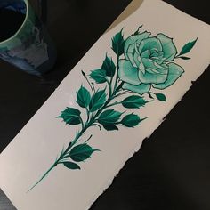 a piece of paper that has been painted with green leaves and a rose on it