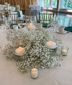 the table is set with white flowers and candles