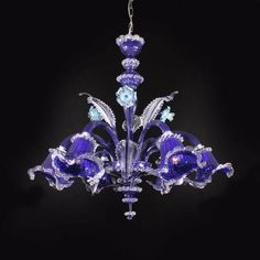 a blue chandelier hanging from a chain on a black background with white flowers