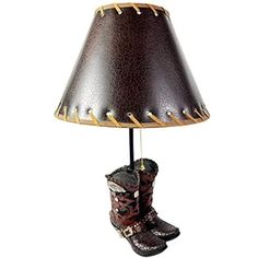 a lamp that is on top of a table with cowboy boots and booties underneath it