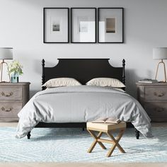 a bedroom with three framed pictures above the bed and two nightstands on either side