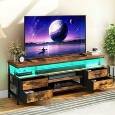 a flat screen tv sitting on top of a wooden entertainment center next to a plant