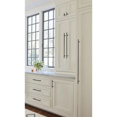 a kitchen with white cabinetry and marble counter tops, along with a large window