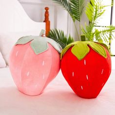 two strawberry shaped pillows sitting on top of a bed