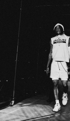 a black and white photo of a man in a basketball uniform walking down the court