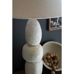 a lamp sitting on top of a table next to a bowl with nuts in it