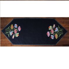 a black table runner with colorful flowers on the edge and fringes in the middle