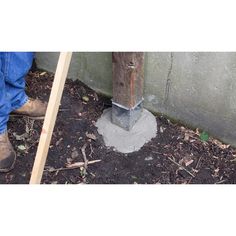 a man standing next to a cement block with a wooden pole sticking out of it