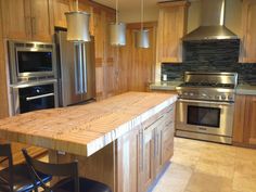 a kitchen with stainless steel appliances and wooden counter tops, along with an island in the middle